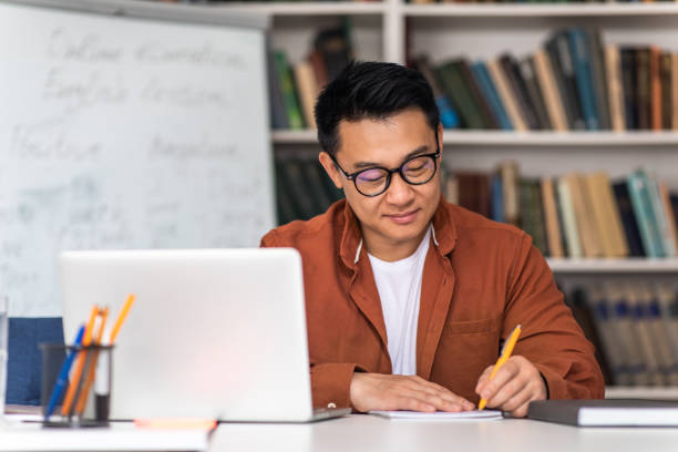 istock Asian Teacher Writing Using Laptop Having Online Lecture In Classroom 1470444555
