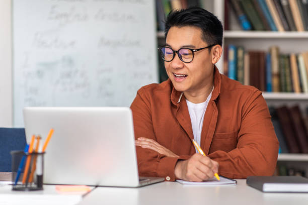 istock Asian Tutor Having Online Class Via Laptop Taking Notes Indoor 1470444556