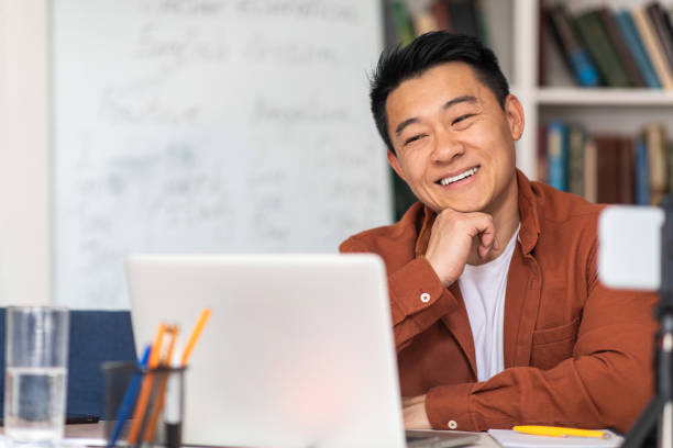 istock Chinese Male Teacher Having Class Video Calling On Laptop Indoor 1470444559