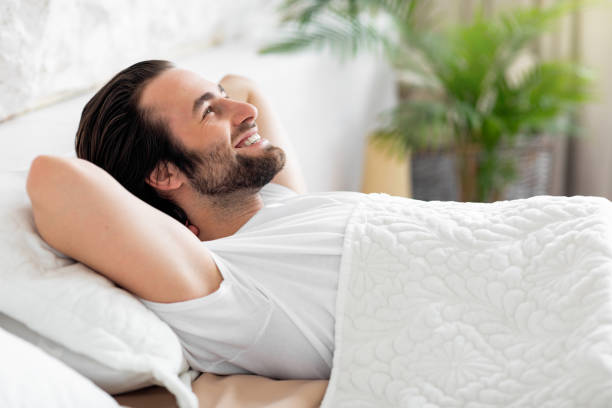 istock Side view of smiling young man relaxing in bed 1470444700