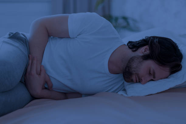 istock Sick man suffering from stomach cramps at night 1470444915
