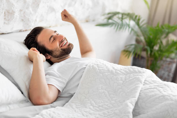 istock Side view of smiling young man stretching in bed 1470444919