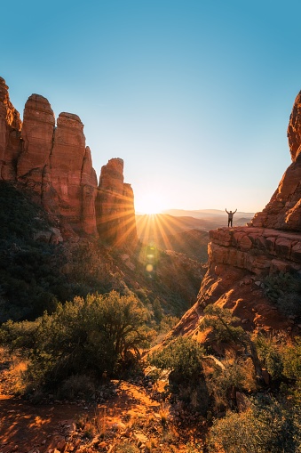 A man standing on top of a rock admiring scenic mountain range in Sedona, Arizona