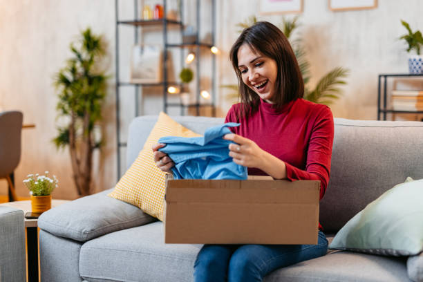 istock Young Woman Unboxing A Package With A New Shirt She Ordered Online 1470447553