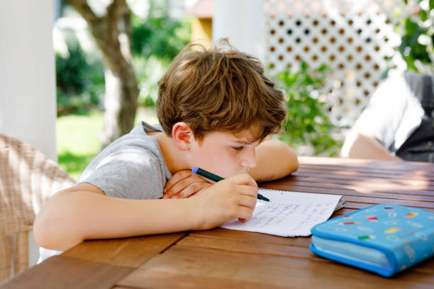 istock Hard-working sad school kid boy making homework during quarantine time from corona pandemic disease. Upset tired child on home schooling in coronavirus covid time, schools closed. 1470448432