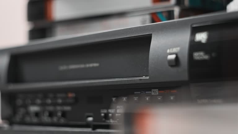 Male Hand Inserts VHS Cassette Into a VCR Video Recorder