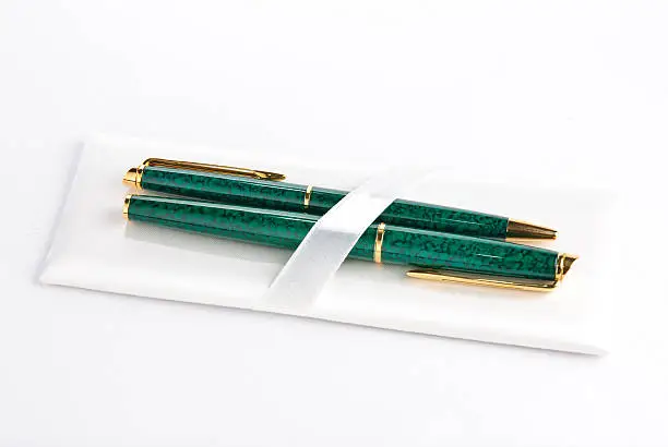 two green and golden stylographs isolated on a white background