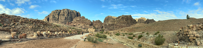 Lone Bedouin figure walks along the Colonnaded Street, Petra, Jordan, Middle East. Petra, built around 300 B.C. by the Nabataean Arabs, is the world famous archaeological site in Jordan's southwestern desert. Capital of the Nabatean Kingdom it seamlessly blends Arab style with Hellenistic and Roman or Byzantine architecture. Accessed via Al Siq, a narrow canyon, it contains tombs and temples carved into the pink sandstone cliffs, hence the 'Rose City' The most famous and iconic structure is Al Khazneh, a temple with an ornate Greek-style facade, also known as The Treasury