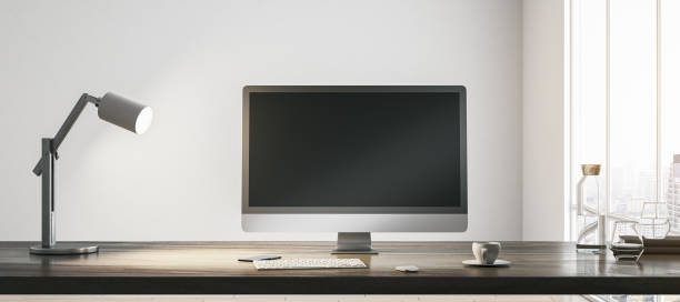 istock Blank dark modern computer monitor with space for your web site or web design on wooden table with coffee cup, keyboard and lamp on light wall background in sunlit room. 3D rendering, mock up 1470453573