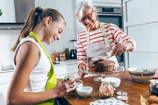 Shot of happy family grandmother and granddaughter making chocolate cake in the kitchen