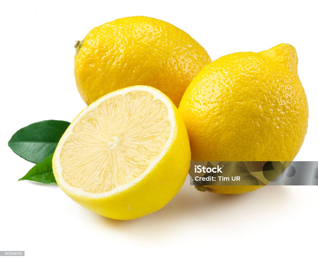 Two and a half lemons on white background Several lemons are arranged on a while background.  Two lemons are whole and uncut.  They are a rich, vibrant yellow color.  One lemon is halved.  The cut lemon displays the interior juicy texture of the fruit.  Two small green lemon leaves sit nearby. Cut Out Stock Photo