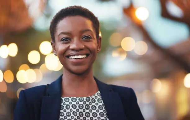 Photo of Smile, confident black woman and portrait in a city with bokeh, lights and blurred background space. Face, traveller and happy African American person in town for fun, break or trip on the weekend