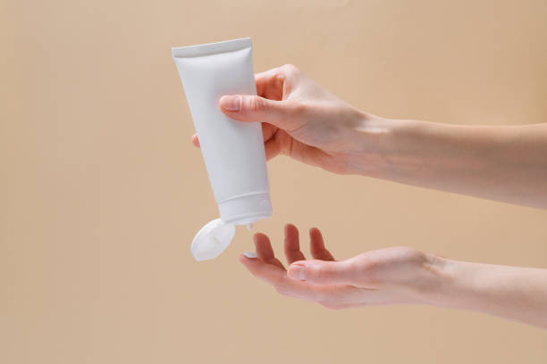 istock Horizontal image of female hands squeezing mockup face cream on finger on beige isolated background. Natural cosmetics for skin care concept. 1470461207
