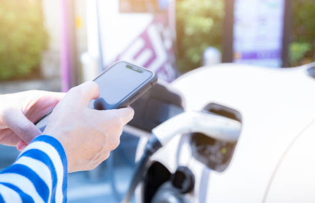 istock Woman using smartphone paying service in mobile app on blur EV car charging at electric vehicle charging station. EV car charging point. Commercial EV car charging station. Sustainability lifestyle. 1470461367