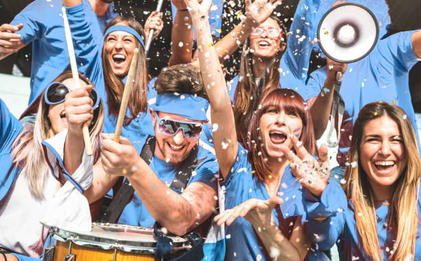 junge amateurfußball-fans jubeln mit fahnen beim lokalen fußball-pokalspiel im stadion-freundes-leute gruppe auf blauen t-shirts, die spaß am sport-weltmeisterschaftsfinale haben - rugby shirt stock-fotos und bilder