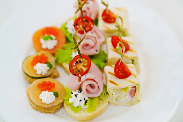 canapes as a treat for the holiday. small sandwiches, rolls and burgers in a plate on the table.