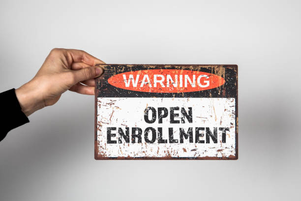 istock Open Enrollment. Warning sign with text on a white background in a woman's hand 1470463538