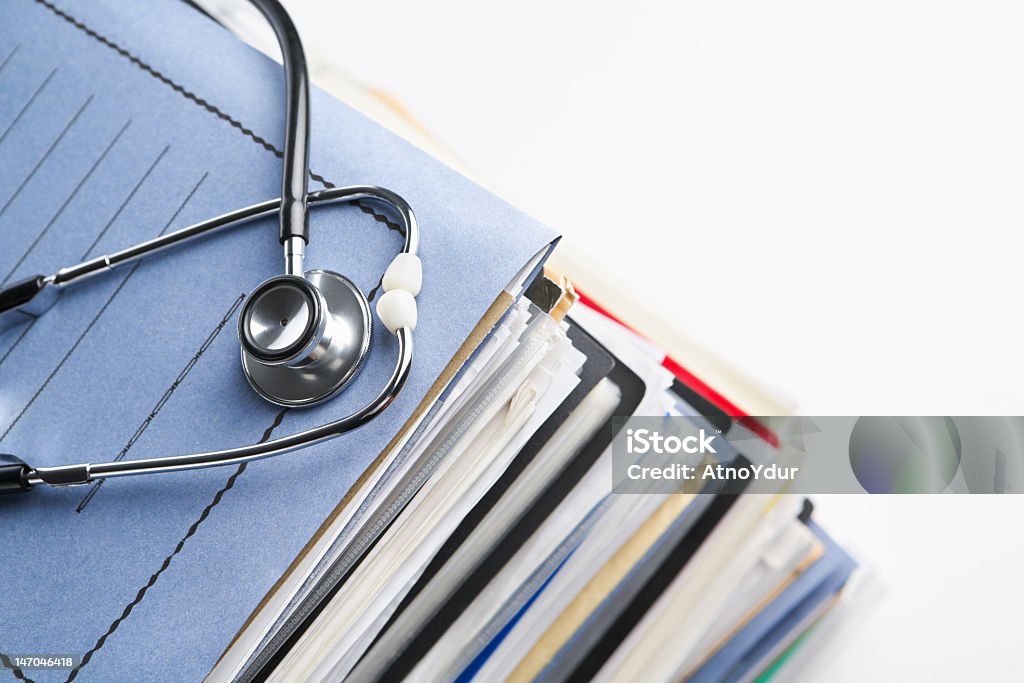 A stack of medical report folders Medical record concept with stetoschope over pile of document. Selective focus on the front side of the stethoscope Copy Space Stock Photo