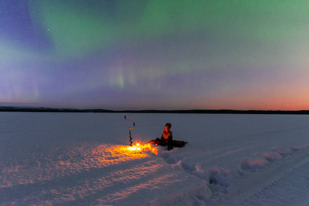 istock Ice fishing with northern lights (aurora borealis) 1470464598