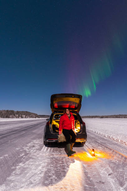 istock Person sitting by the car under northern lights (aurora borealis) 1470464694