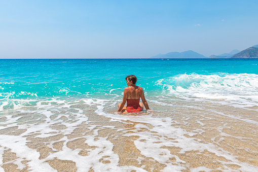Young redhead girl in sunglasses and bikini on Elafonissi beach, west Crete, Greece. Summertime season