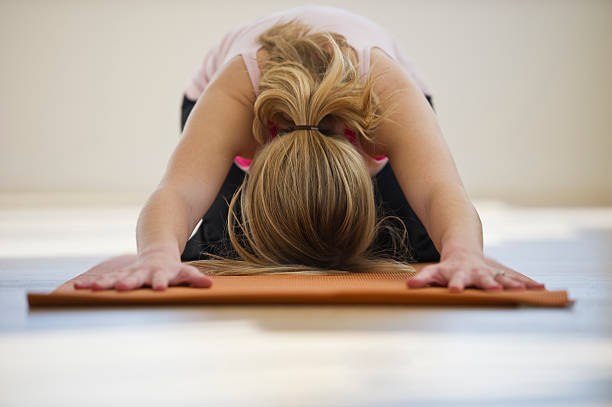 woman doing yoga on mat in studio stock photo