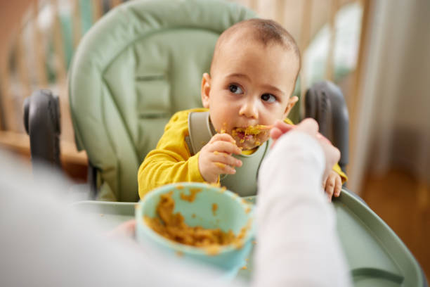istock Mother spoon feeding her baby son at home 1470471173