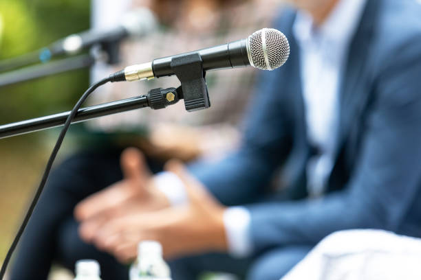 istock Microphone in focus at round table meeting or business event 1470473517