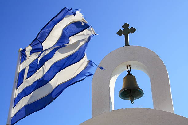 bell of a greek chapel with greek flag