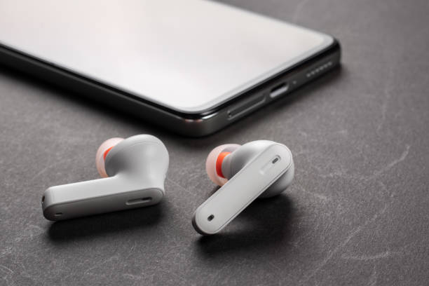 istock Wirelsss white headphones and smartphone on dark background 1470480256