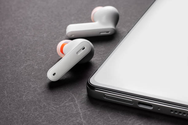 istock Wirelsss white headphones and smartphone on dark background 1470480290