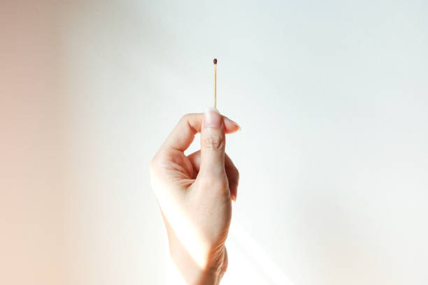 istock Hand with a match or matchstick on white cement wall. 1470481067