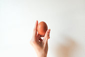brown egg in asian woman hand on white background.