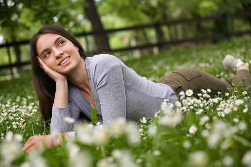Young woman lying in a spring flower field. About 25 years old, Caucasian brunette.