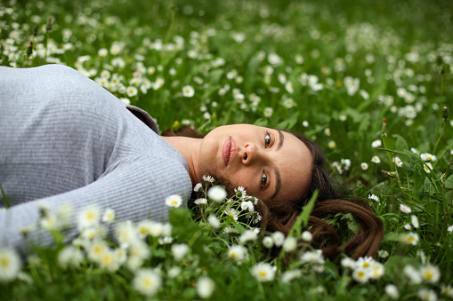 Young woman lying in a spring flower field. About 25 years old, Caucasian brunette.