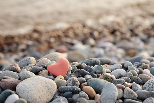 red stone in  shape of heart on  beach by  sea