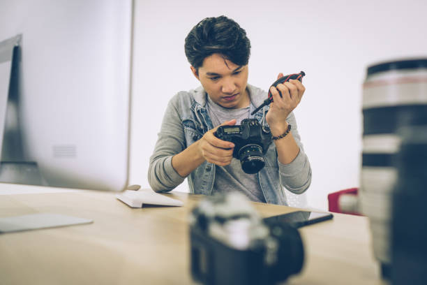 istock Asian Photographer cleaning blowing the dust from his camera 1470486473
