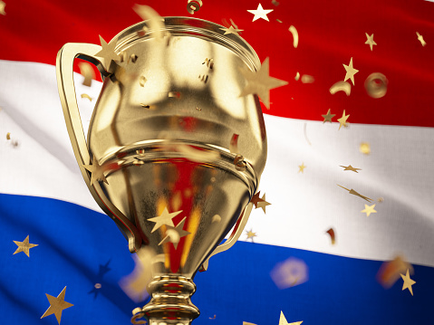 Netherlands Championship Concept Star Shaped Confetti Falling Onto A Gold Trophy Cup with Dutch Flag. 3D Render