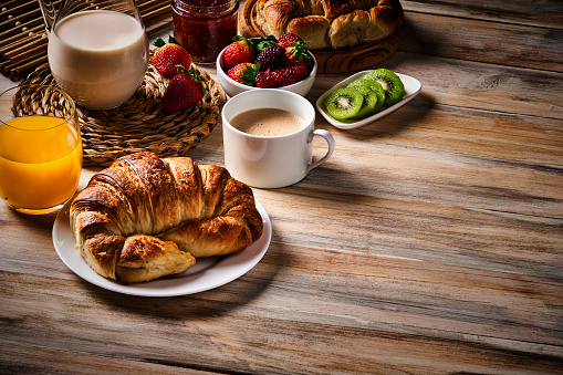 Food theme series: Food theme series: Breakfast with cup of coffee, croissants, marmalade, and fruits on wooden table