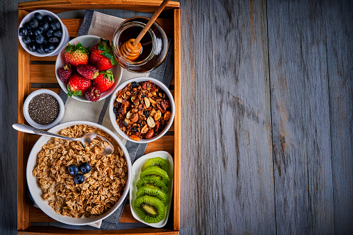 Healthy eating series: Top view of healthy breakfast on rustic wooden table: Yogurt, oatmeal, salad fruit, granola and honey ready to eat. Healthy lifestyle with copy space.