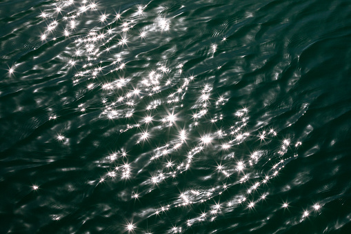 The sun shines on the green water early in the morning, reflecting the stars