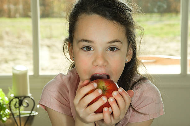 istock brown haired child eating an apple 147049328