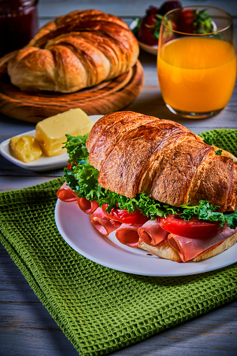 Food theme series: Croissant sandwich breakfast with orange juice on a rustic table