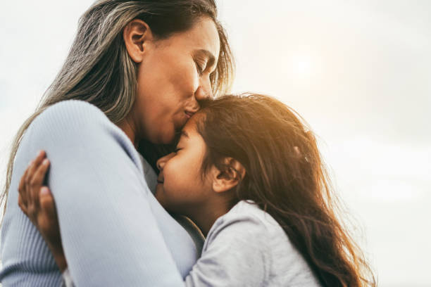 Happy latin mother and daughter having tender moment together outdoor - Focus on mom eye stock photo