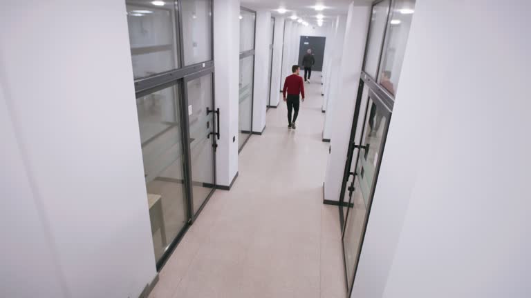 Colleagues walk and talk in hallway of office