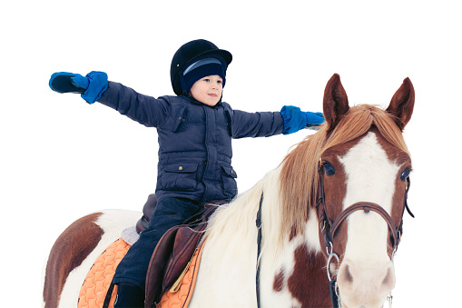 A boy child rides a horse in winter through a snowy forest, isolated on a white background