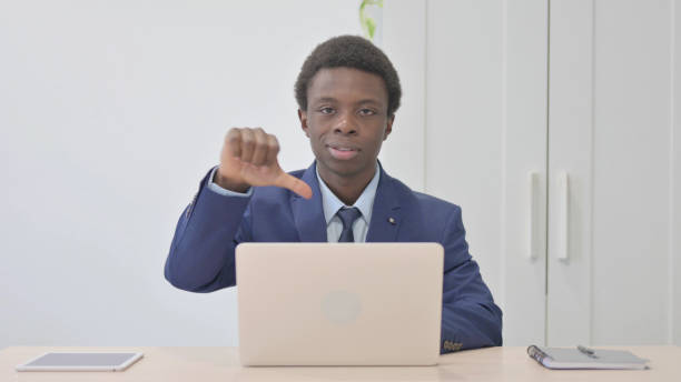 istock Thumbs Down by Young African Businessman Working on Laptop 1470499183