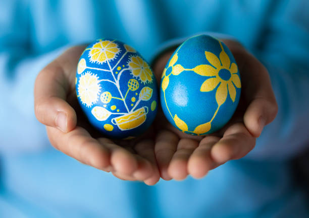 우크라이나 국가 상징으로 파란색과 노란색으로 칠해진 화려한 부활절 달걀을 들고 있는 가려진 어린 소녀 - two eggs 뉴스 사진 이미지