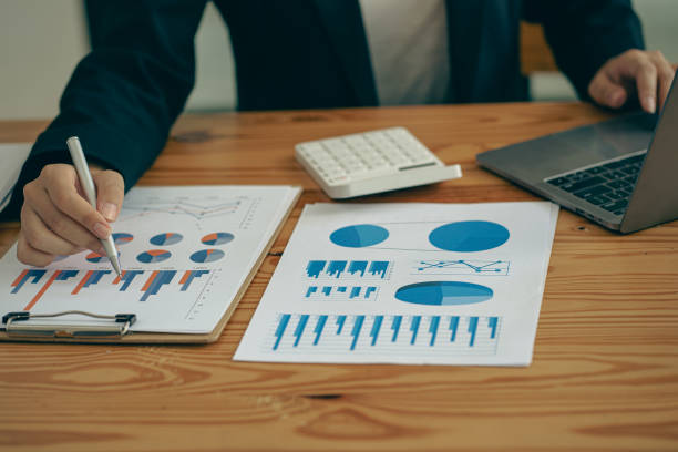 istock Businessman hand holding a pen pointing in document, financial graph, plan, marketing graph. Financial investment and business strategy data chart report and working on laptop in office 1470501363