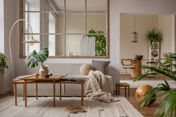 istock Open space interior with modular sofa, wooden coffee table, big window, beige rug, braided plaid, pillows, round table, lamp, plants, slippers, ball and personal accessories. Home decor. Template. 1470504854